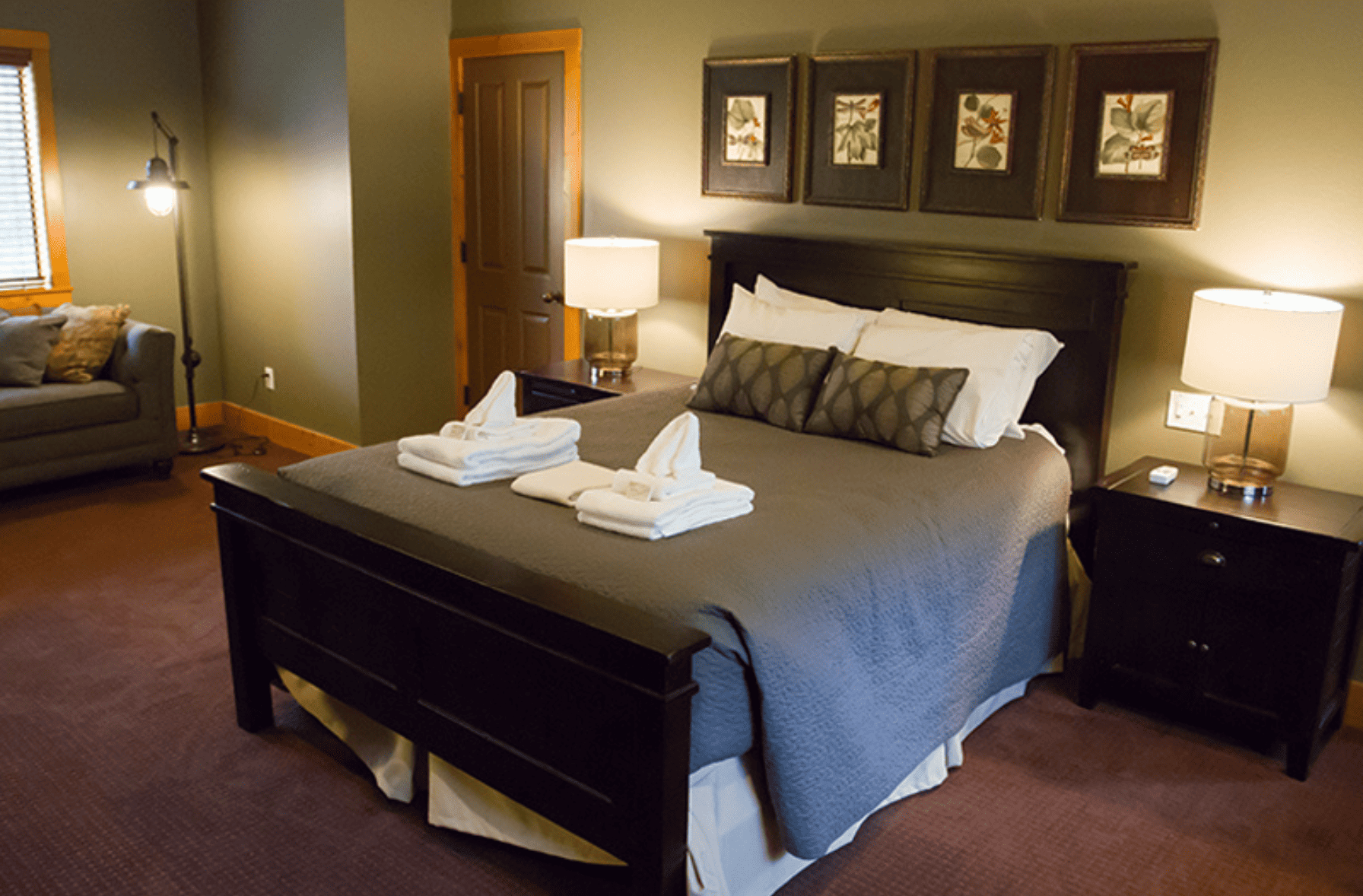 Inside bedroom of the engle house. Bed with dark bedding and towels on the bed